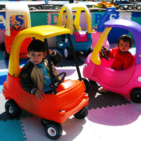 Untitled Children riding toy cars outside